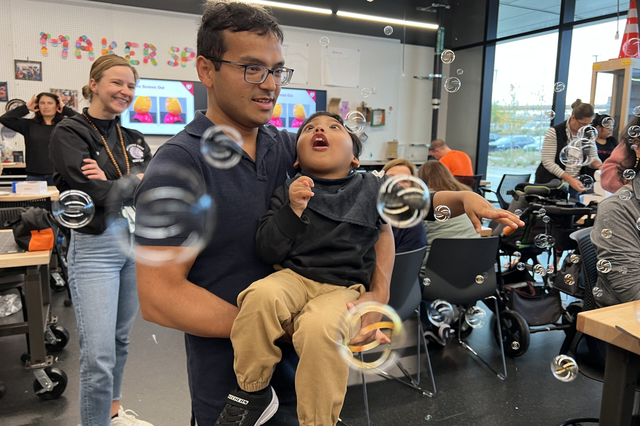 Yuvan Khadgi&comma; held by his father Naresh Khadgi&comma; smiles at bubbles during an adaptive toy workshop&period;