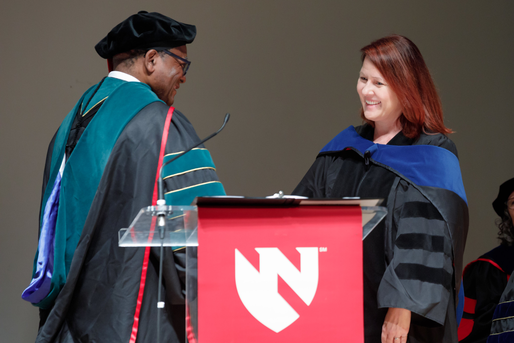 Dele Davies&comma; MD&comma; dean for graduate studies&comma; greets UNMC Graduate Studies alumnus Robin Cotter&comma; PhD&comma; before she gives the keynote address at the 2023 Winter Honors Convocation&period;