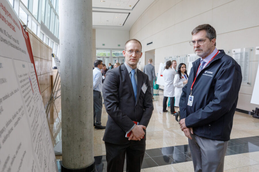 Mark Cheney&comma; MD&comma; left&comma; explains his poster to an attendee&period;