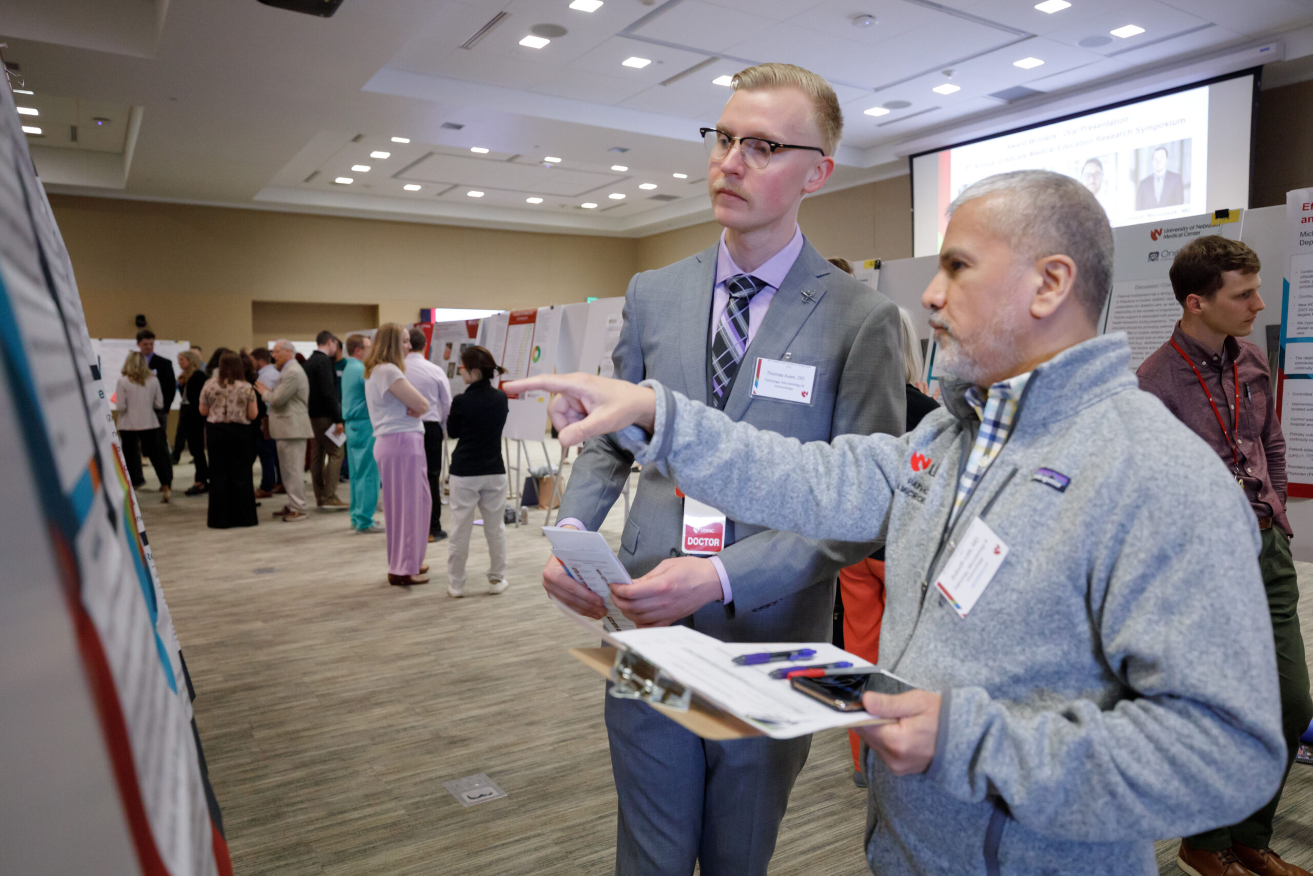Thomas Auen&comma; DO&comma; left&comma; a winner for oral presentation&comma; reviews a poster with Subodh Lele&comma; MD