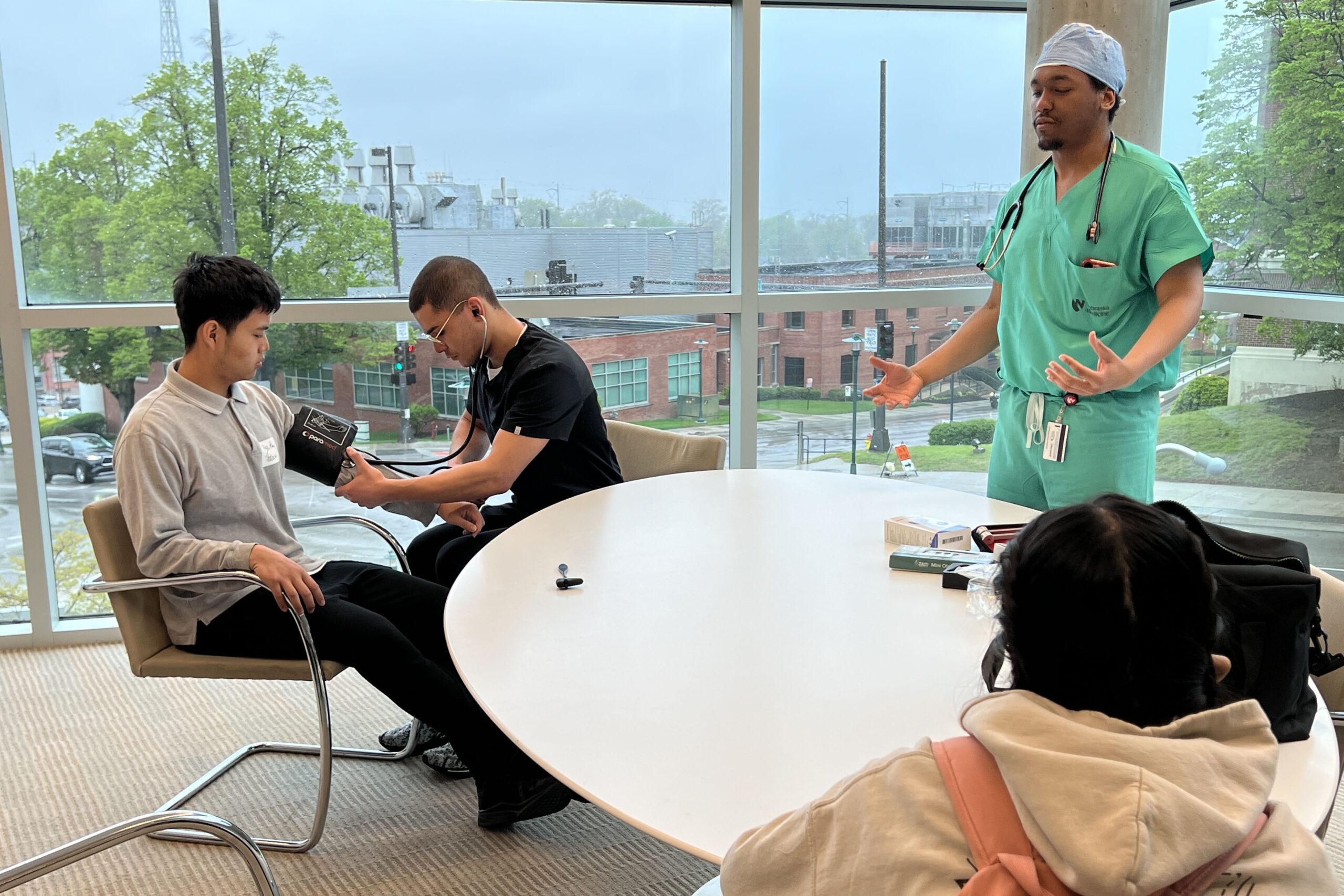 Medical students Mark Carter&comma; MD&comma; in black&comma; and Austen Washington&comma; in green&comma; discuss medical exams with Benson High School students&period;