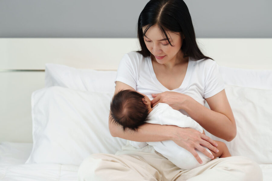 A mother breastfeeding newborm baby on a bed