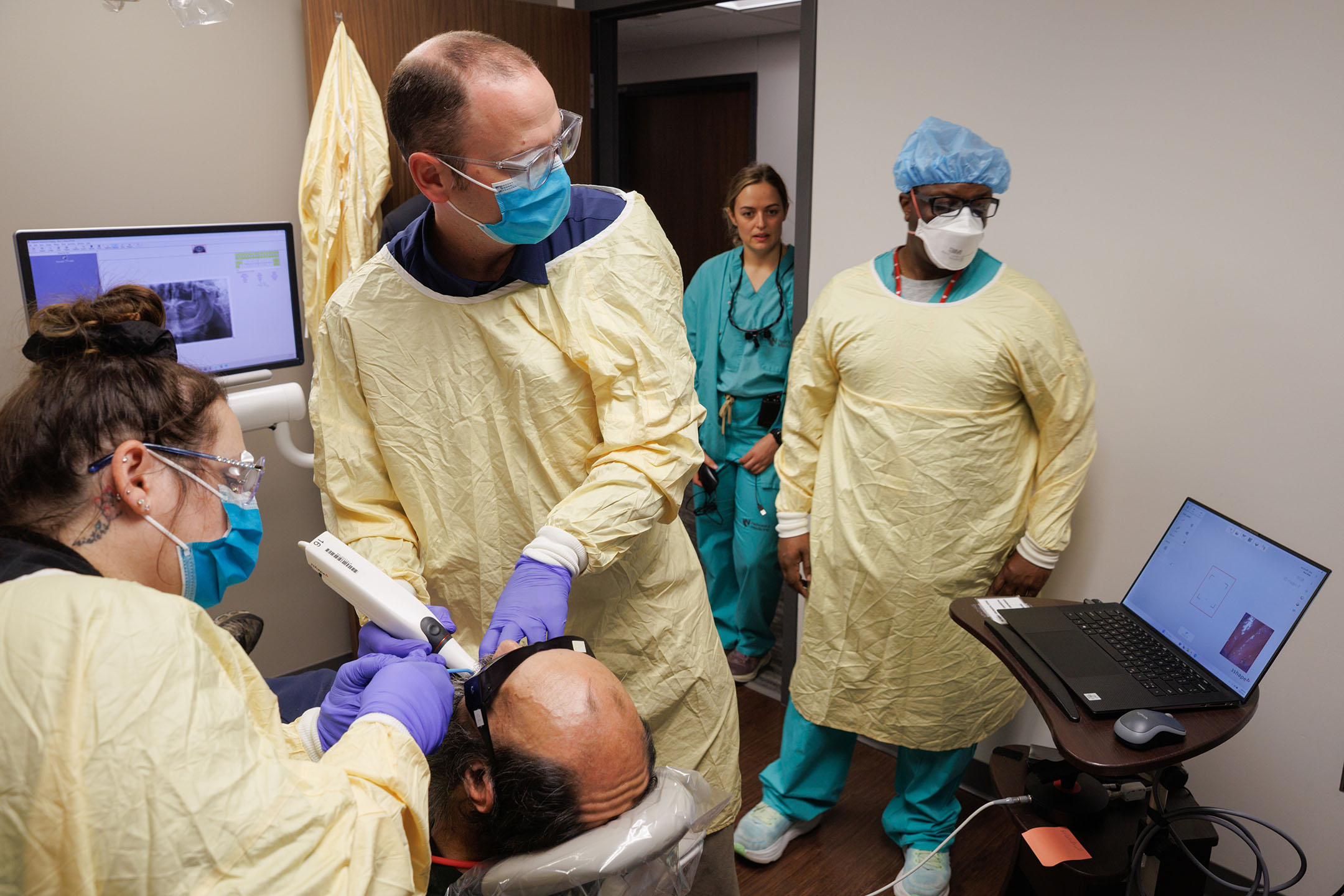 A team of dental faculty, residents and assistants works with a dental patient