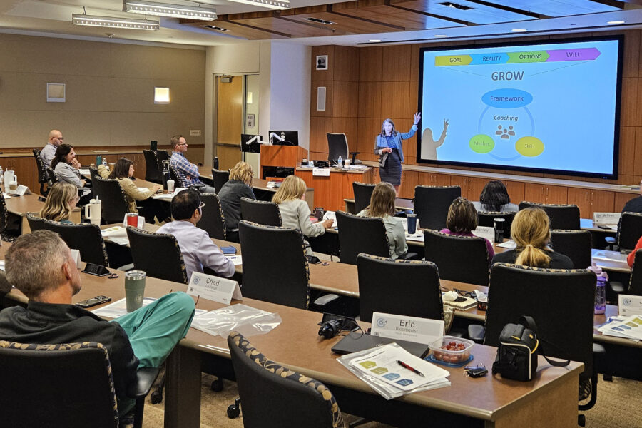A faculty member presents at a conference in a lecture room full of attendees