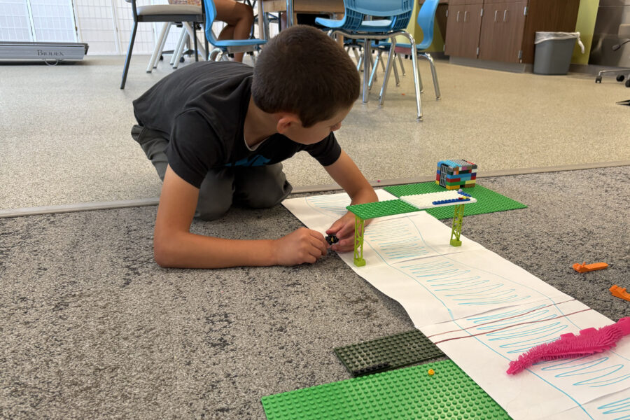 George Robertson decorates a makeshift riverbank with Lego creations during the Munroe-Meyer Institute Department of Occupational Therapy's Lego Camp.
