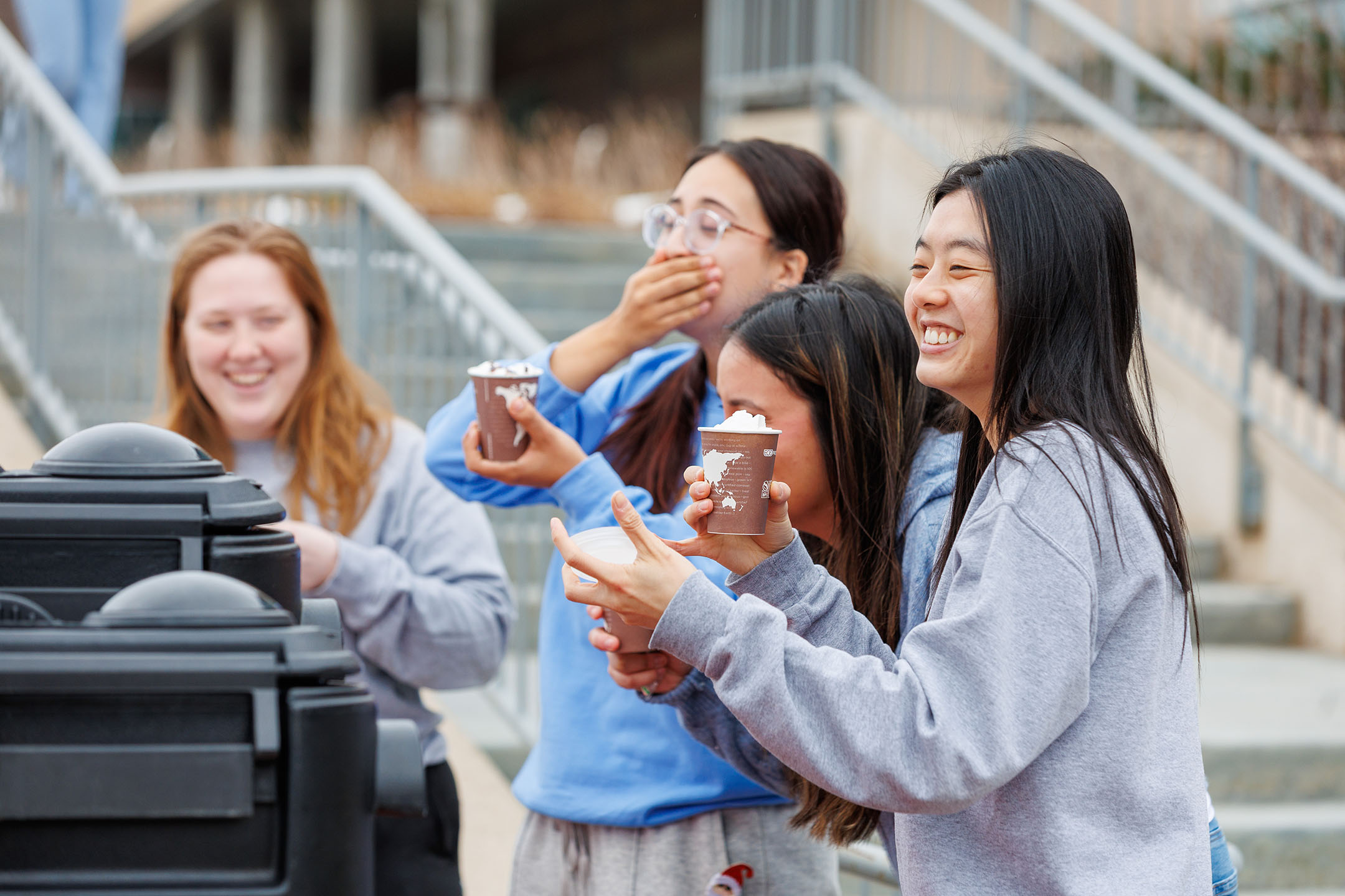 Four female students smiling and laughing as they make hot chocolate during De-Stress Week