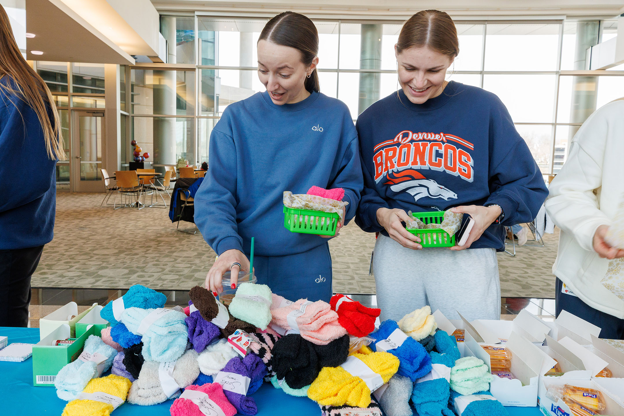 Two students smiling at they go through the Cozy Baskets line