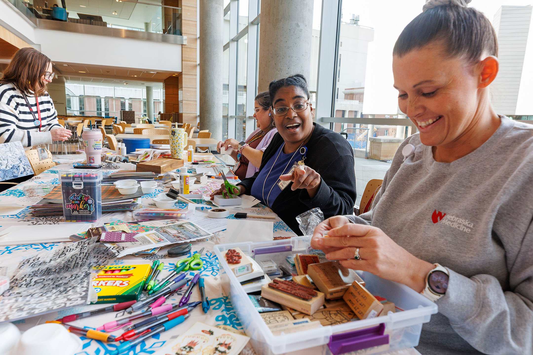 People smile and motion as they make crafts during De-Stress Week