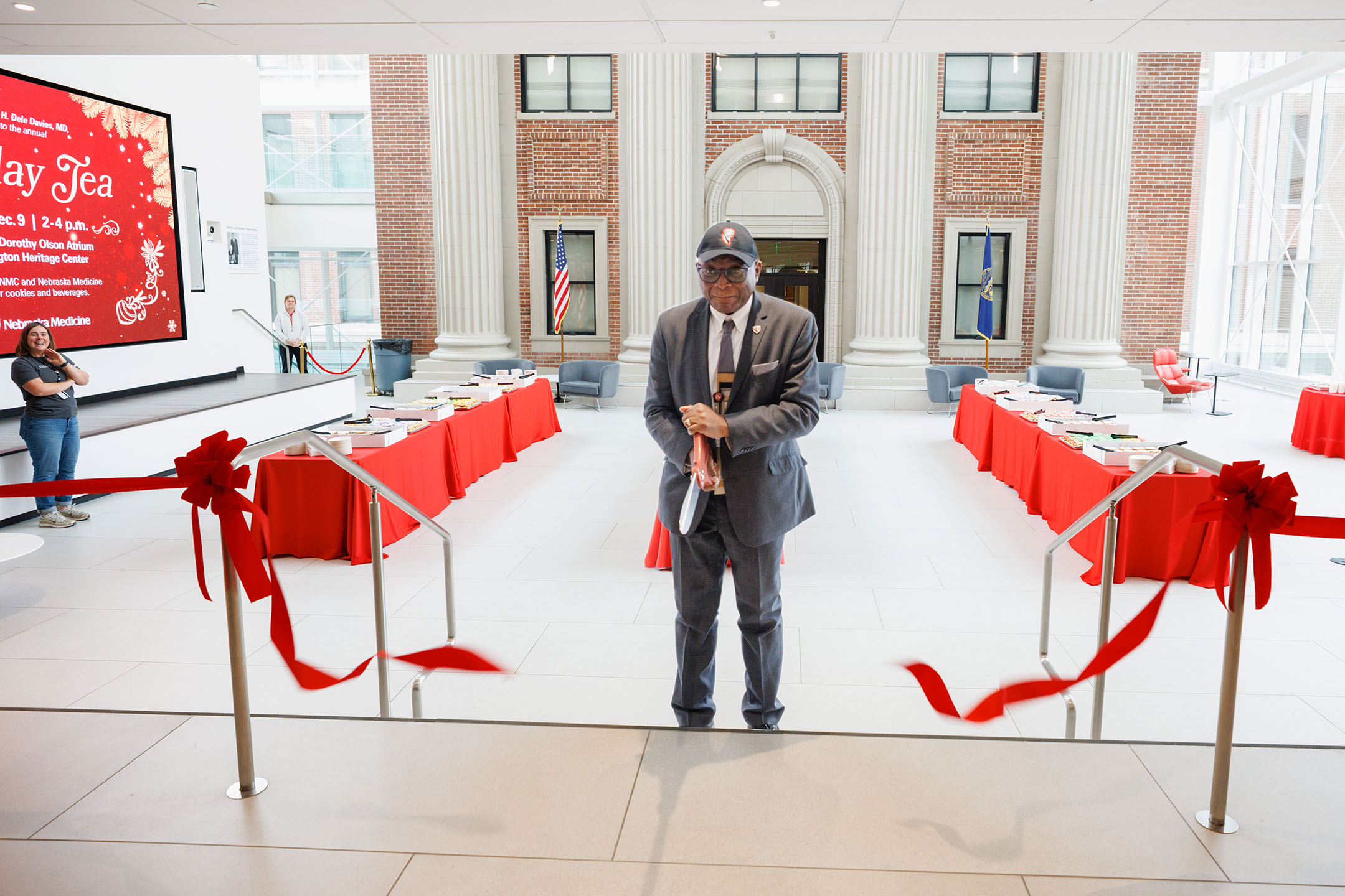 UNMC Interim Chancellor H&period; Dele Davies&comma; MD&comma; cut the ribbon on the Chancellor's Holiday Tea&comma; an annual tradition at UNMC held in December and in the middle of De-Stress Week&period; Off to the left are UNMC's events team with UNMC Strategic Communications&colon; Kacie Baum&comma; senior manager for events and community engagement&comma; and Candace Peteler&comma; campus events center coordinator&period;