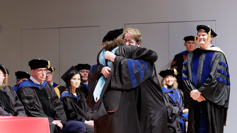 A mentor and mentee hug after hooding at the winter Honors Convocation&period;