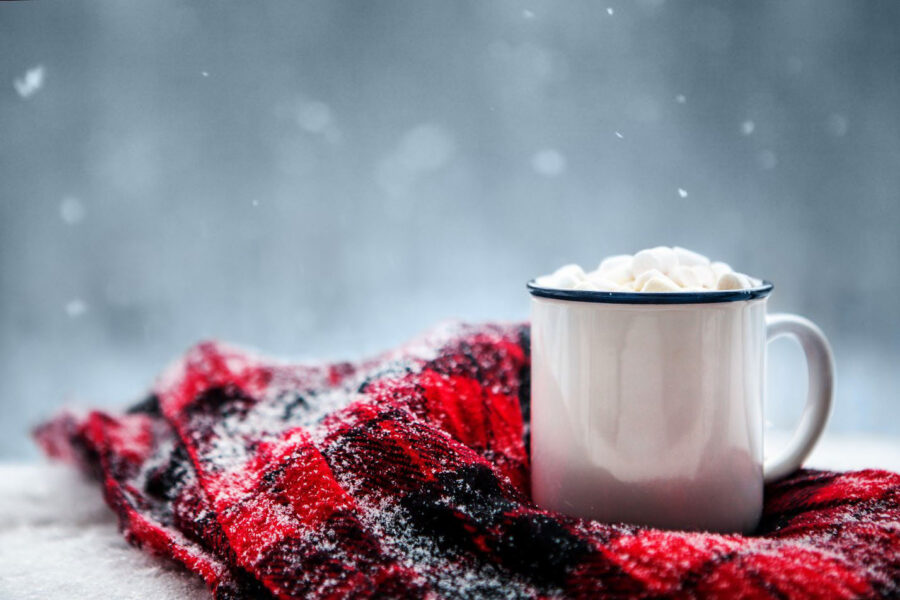 A mug of hot chocolate wrapped in a blanket in the snow