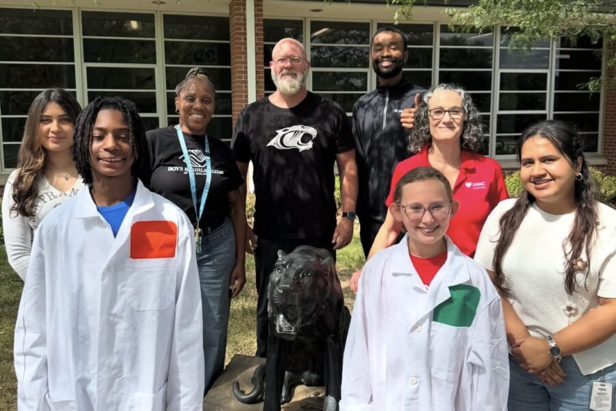 Morton Magnet Middle School students in white lab coats were joined by Laiba Anwar&comma; left&comma; GSA vice president&comma; Annant Kaur&comma; GSA president&comma; far right&comma; and Karen Gould&comma; PhD&comma; in red shirt&period; In the back row are Stephanie Henderson&comma; BGC director of the Morton Club&comma; Morton principal Matt Williams&comma; EdD&comma; and Rodney Conyers Jr&period;&comma; youth development director of the Panther Pack&period;