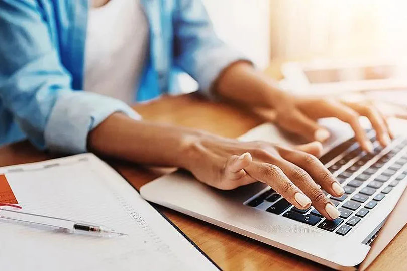 A woman working at a table and typing on a laptop computer