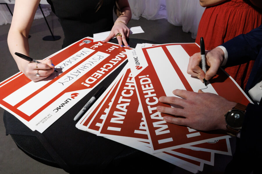 Senior medical students write their match locations on signs at UNMC's 2026 Match Day&period;