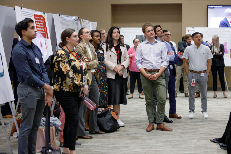 Graduate students stand at attention to listen to a presentation during the 6th Annual Graduate Medical Education Research Symposium held in the Truhlsen Events Center, Michael F. Sorrell Center for Health Science Education.