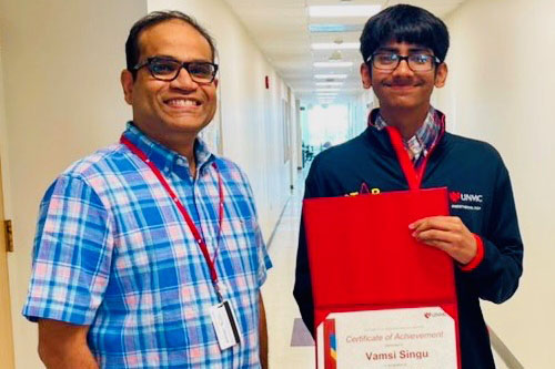 Gurudutt Pendyala, PhD, and Vamsi Singu posing for a photo in a hallway as Singu holds a Certificate of Achievement
