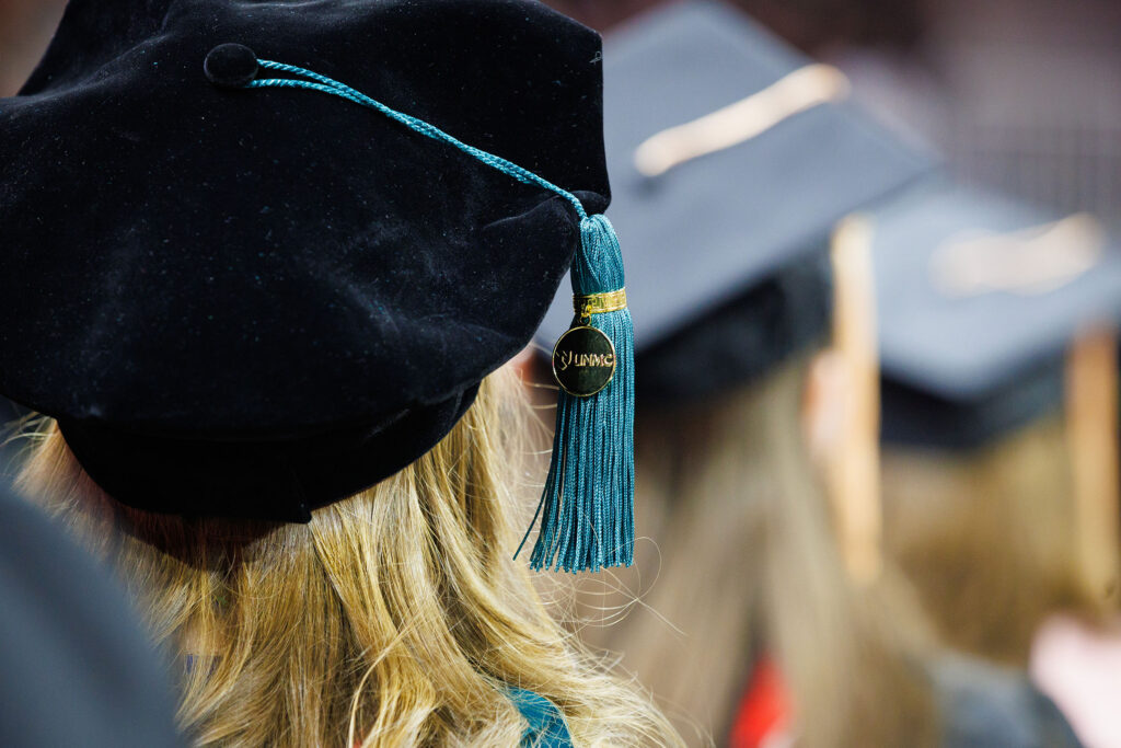 A UNMC graduate wears the ceremonial attire, with focus on her cap and tassel.