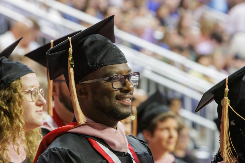 A UNMC graduate in commencement attire smiles.
