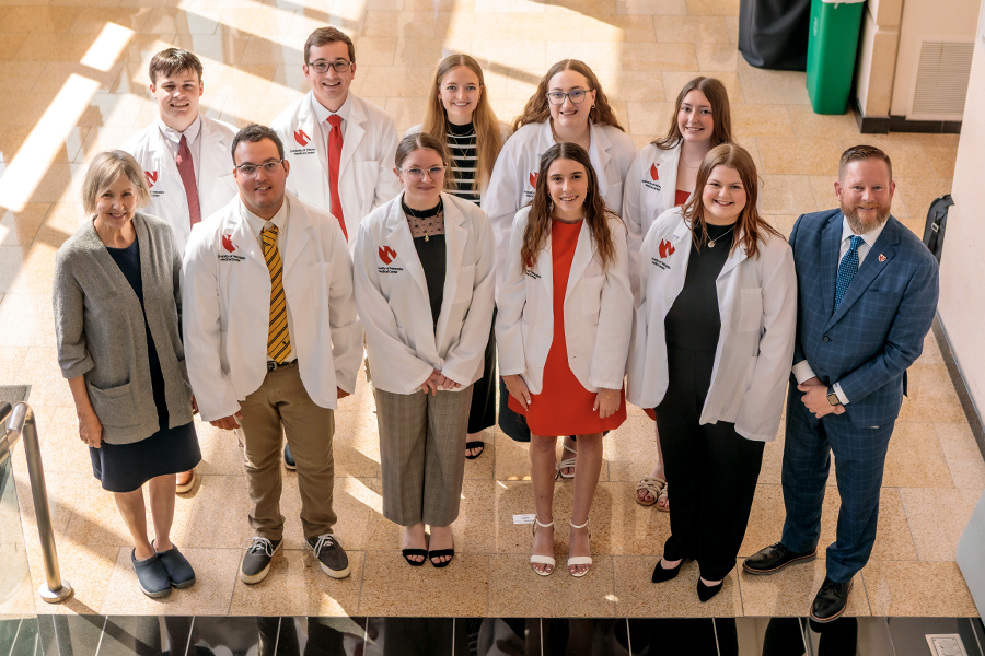 Group photo. Linda Sobeski, PharmD, and Don Klepser, PhD, flank the inaugural class of UNMC’s College of Pharmacy in Kearney. Front row, from left, in white coats are Vance Sayer, Brianna Plaster, Megan Lukert and Ella Johnson. Back row, Brady Spotanski, Carter Schultz, Kiernan Bierman, Bethany Smallwood and Lexi Bode. Dr. Klepser is the Joseph D. Williams endowed dean; Dr. Sobeski is the program’s associate dean.