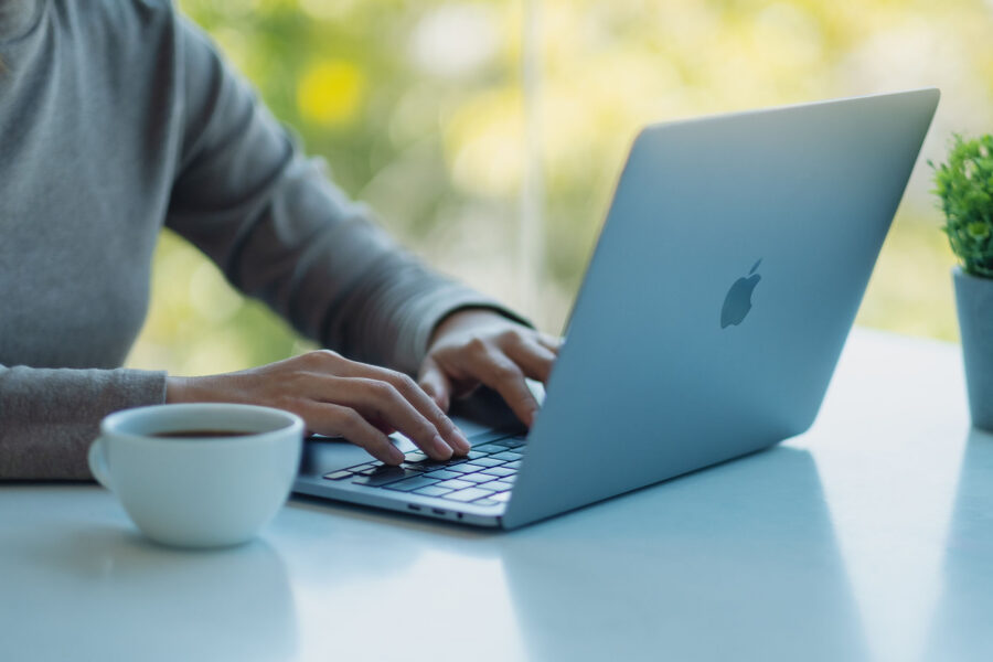 A woman using and typing on Apple MacBook Pro laptop computer on the table in office