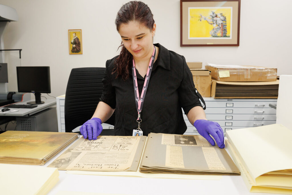 Savannah Falter, a collections specialist for the McGoogan Health Sciences Library, goes through some of the items in the College of Nursing collection Friday Nov. 21, 2025. The collection was previously housed in the College of Nursing and was recently donated to the library. Here, Falter looks through scrapbooks.