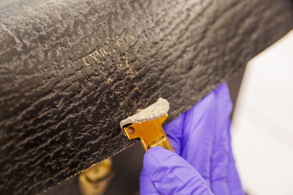 Savannah Falter, a collections specialist for the McGoogan Health Sciences Library, goes through some of the items in the College of Nursing collection Friday Nov. 21, 2025. The collection was previously housed in the College of Nursing and was recently donated to the library. Here, a nurse bag shows a barely legible “UNMC CON” embossed on it.