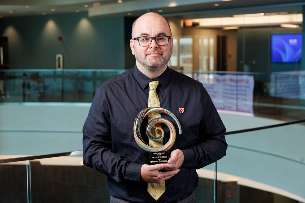 A posed photo of Paul Dye holding his Catalyst for Education Award