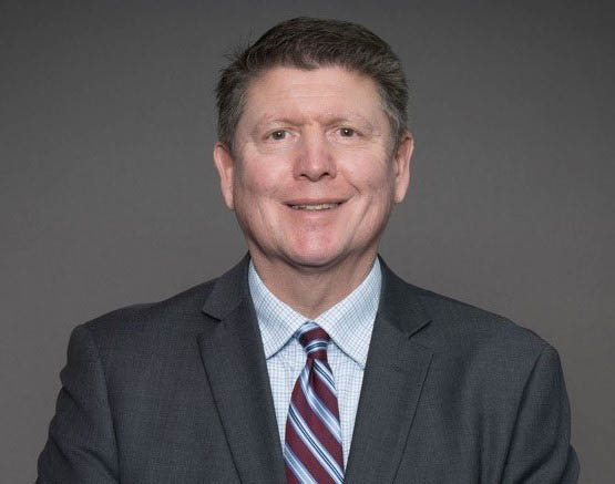 Professional headshot of Clark Rosenlof, in a dark suit jacket with a striped tie.