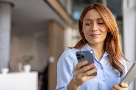 A businesswoman looks down at the cell phone in her hand