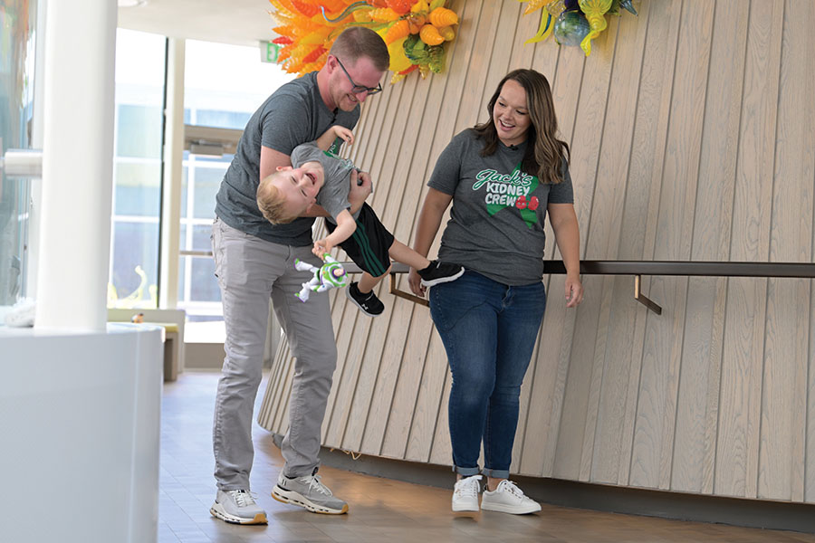 A joyful moment as a couple playfully swings a laughing child between them indoors.