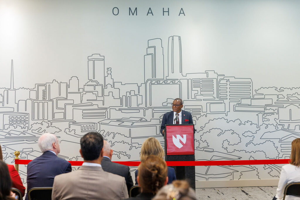 A ribbon cutting event was held Friday July 17, 2026, for the new student housing building on the University of Nebraska Medical Center campus. Here, UNMC Chancellor H. Dele Davies, MD, speaks at a podium with a mural of downtown Omaha behind him.
