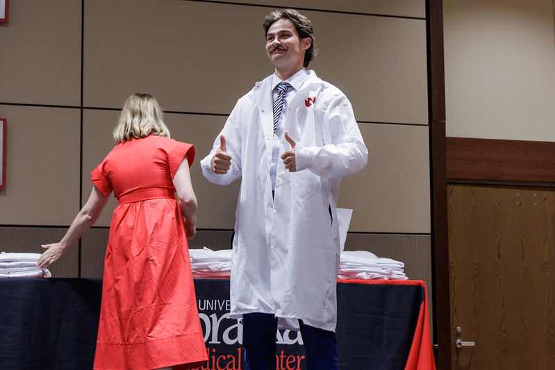 A UNMC College of Dentistry student gives two thumbs up upon donning his new white coat.
