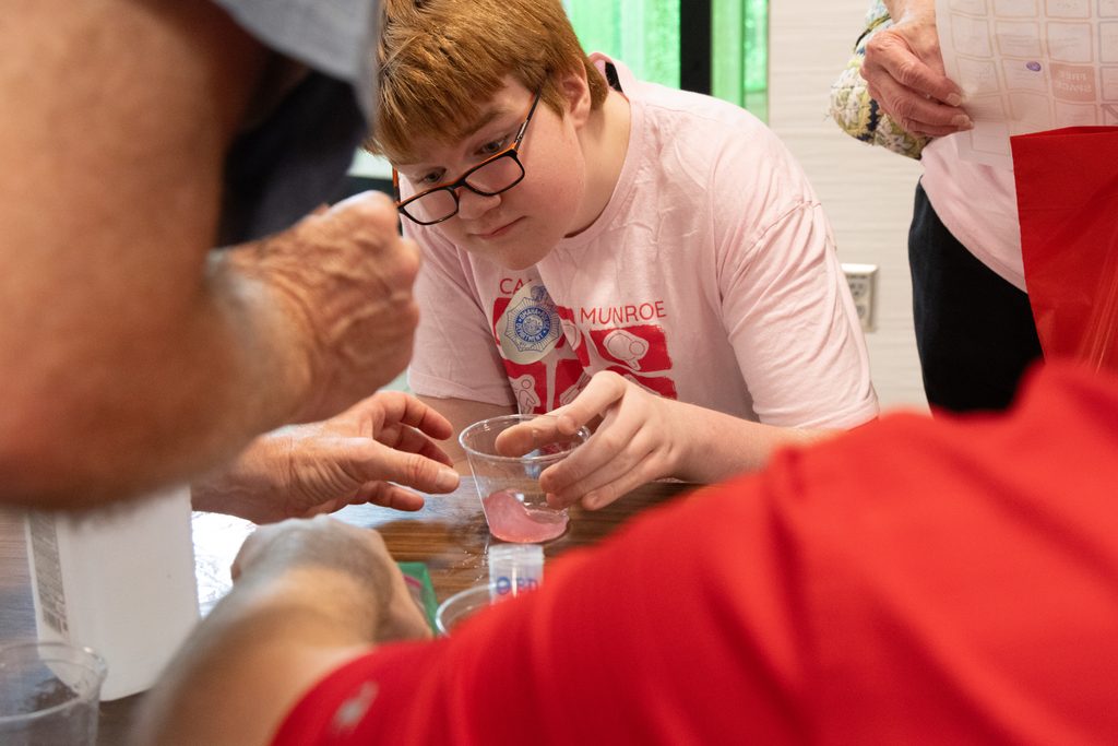 An MMI visitor holds a cup filled with pink liquid during a hands-on activity at the institute's High 5 event.