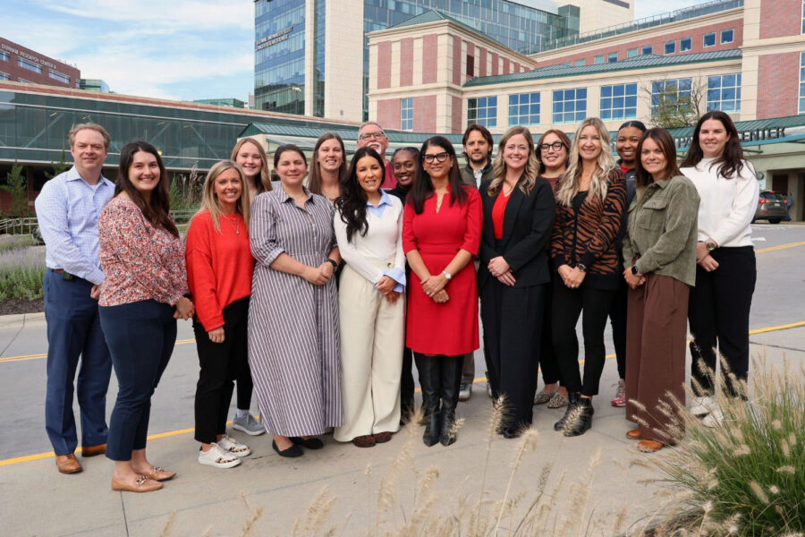 Members of the EMBRACE program pose in front of the Durham Outpatient Center&period; From left&comma; Neil Hamill&comma; MD&comma; EMBRACE medical director&semi; Elizabeth Reisher&comma; PhD&comma; clinical informaticist&semi; Lora Bogatz&comma; manager of women and infants services&semi; Rebecca Rimsza&comma; MD&comma; STAMPP medical director&semi; Courtney Thomas&comma; EMBRACE nurse care coordinator&semi; Sarosh Rana&comma; MD&comma; EMBRACE founder and executive director&semi; Briley Patterson&comma; EMBRACE program manager&semi; Mel Buman&comma; EdD&comma; STAMPP director&comma; women and infant services director&semi; Brianna Heneger&comma; EMBRACE ultrasound lead&semi; Michelle Pieters&comma; clinical research projects coordinator&semi; Chelsey McLaurine&comma; clinical research projects coordinator&semi; Sallie Weathers&comma; marketing and communications specialist&semi; Santiago Ortiz Barragan&comma; clinical research projects coordinator&semi; Destiny Cole&comma; community health navigator&semi; Rick Blum&comma; UNMC Department of OB&sol;GYN administrator&semi; KP Gesch&comma; EMBRACE maternal care educator&semi; and Jasmine Fischer&comma; EMBRACE maternal care educator&period;