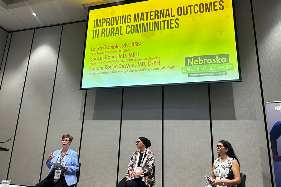 On far right, Dr. Sarosh Rana, and screen with "Improving Maternal Outcomes in Rural Communities" displayed