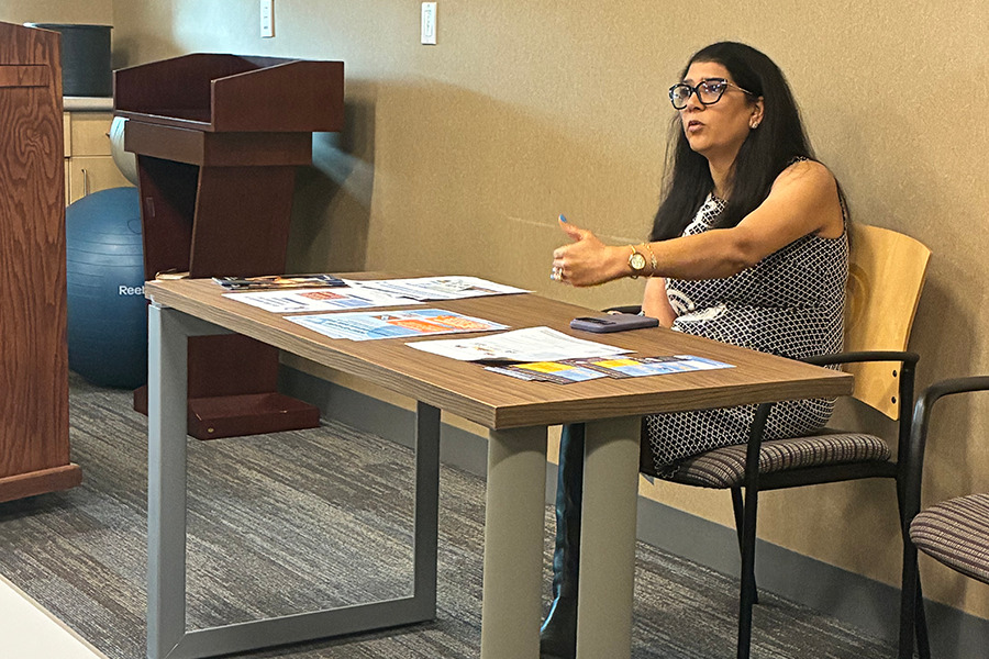 An adult female with dark hair sitting a table and teaching.