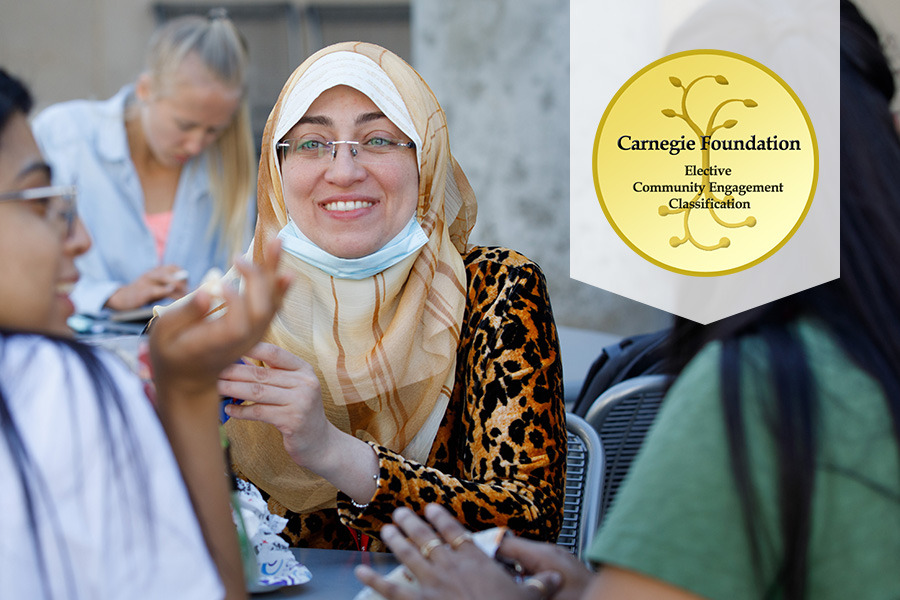 Students sit at table talking with graphic of Carnegie Foundation certification seal in top right corner