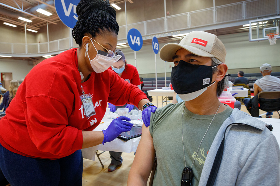 Health care worker gives vaccine shot to community member