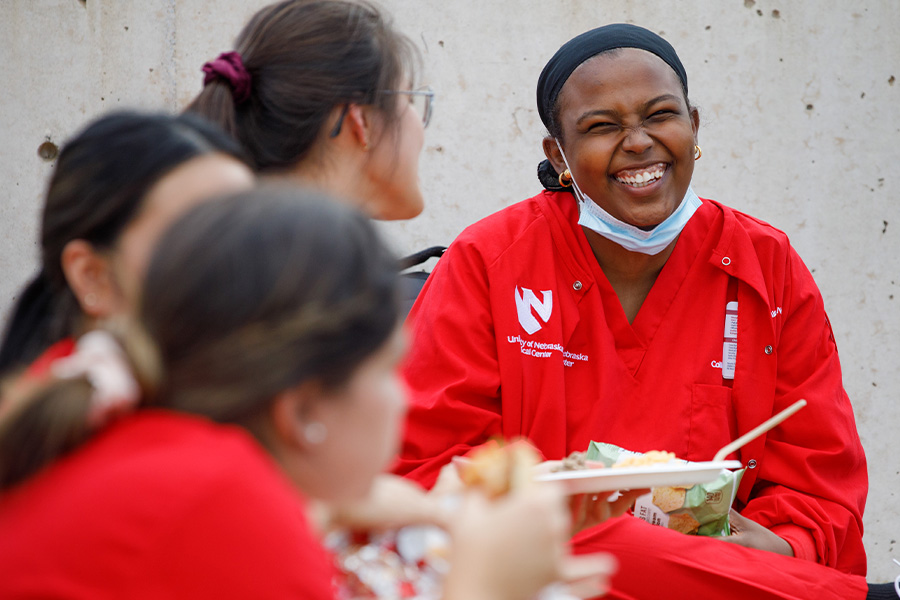 Person laughs with a group of friends while eating lunch