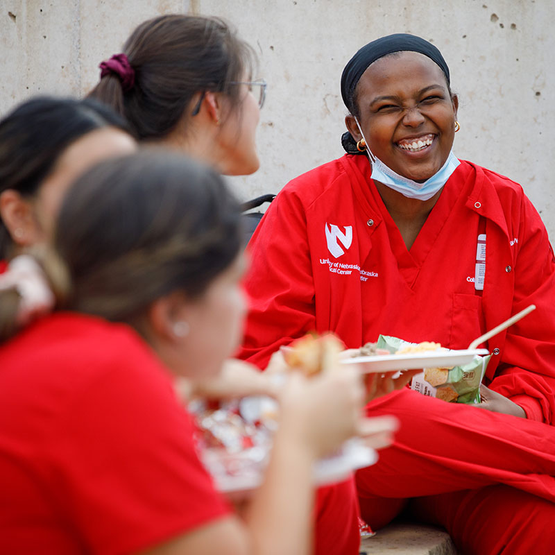 Person laughs with a group of friends while eating lunch