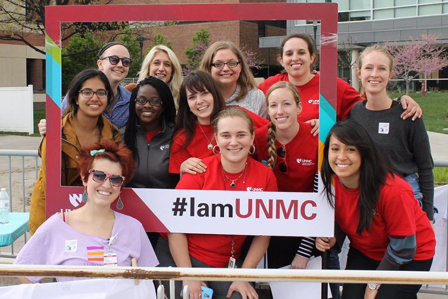 Members of the student group pose together with a frame that says I am UNMC