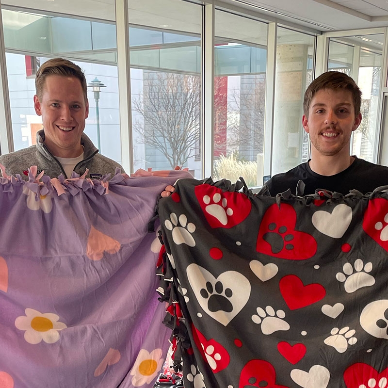 Students hold up blankets they created 