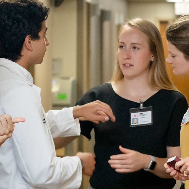 Faculty stands in hallway talking to a student at the clinic