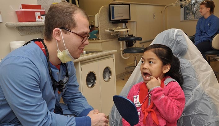 Ingrid Gonzales, 6, shows third-year dental student Jon Isaacson her teeth at the annual UNMC College of Dentistry Children's Dental Day on Feb. 2. (Photo by Margaret Cain.)