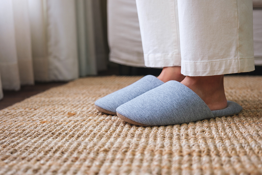 person's lower legs and feet wearing slippers