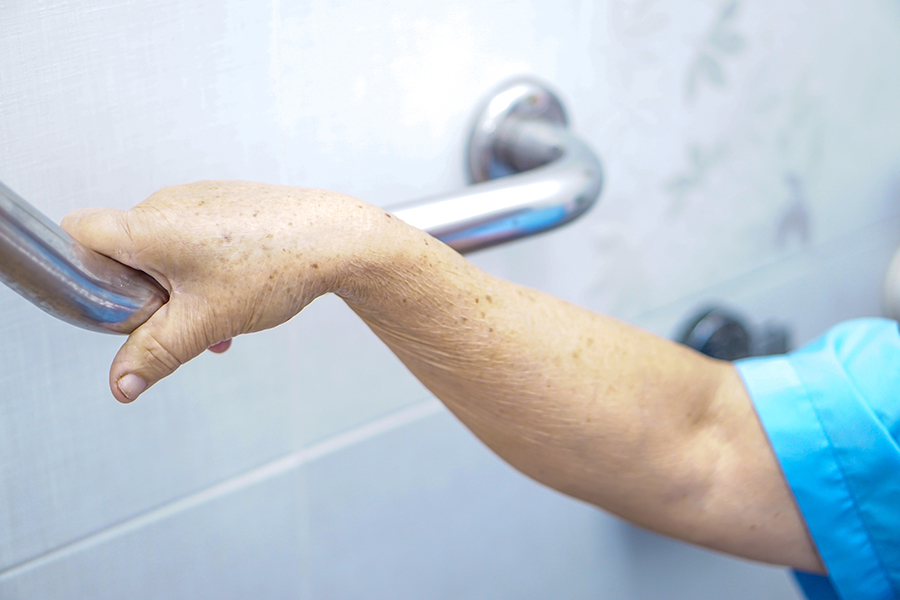 Elderly person holding a bathroom handrail 