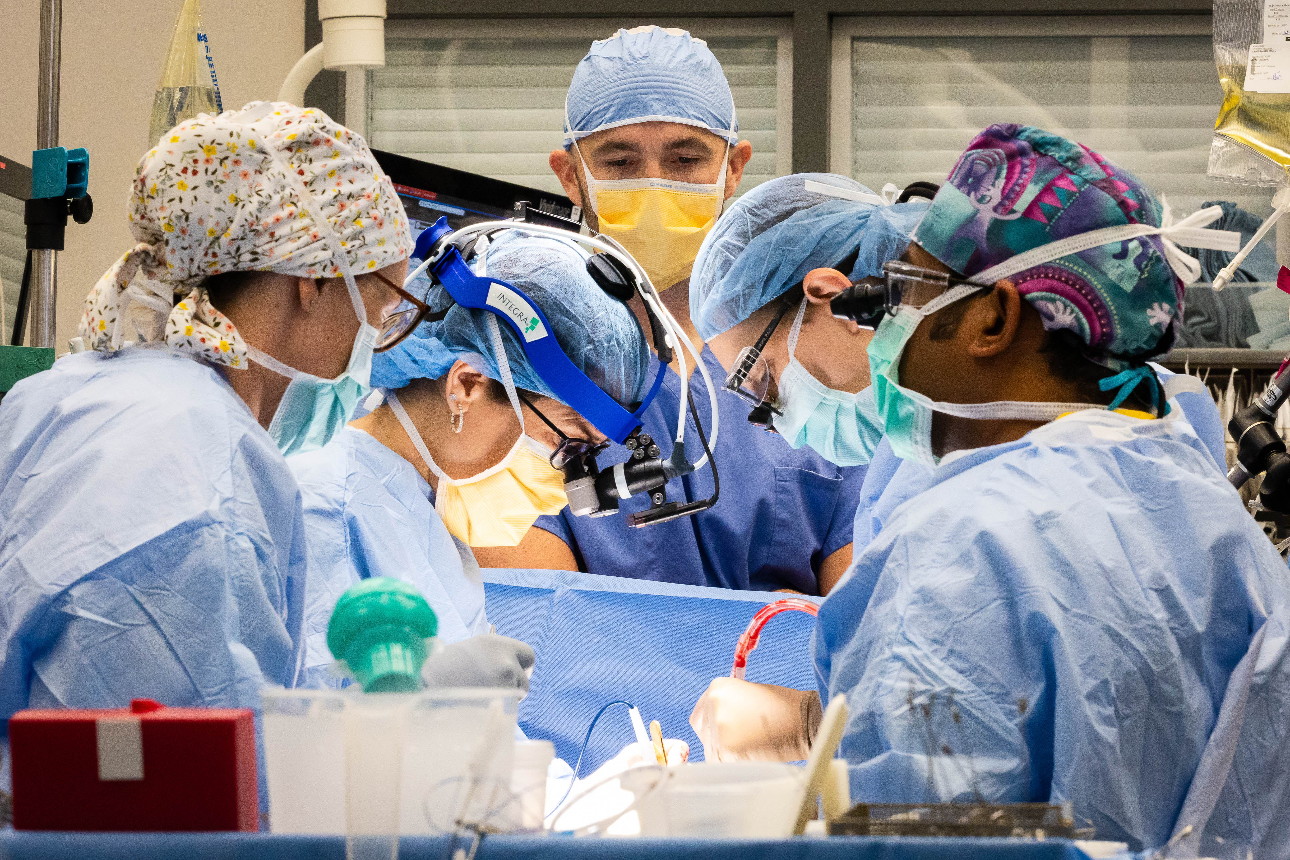 child looks at camera while doctor in the background looks at hand in cast