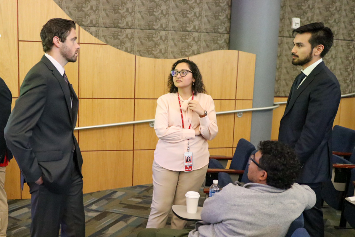three people talk to one another while standing in an auditorium
