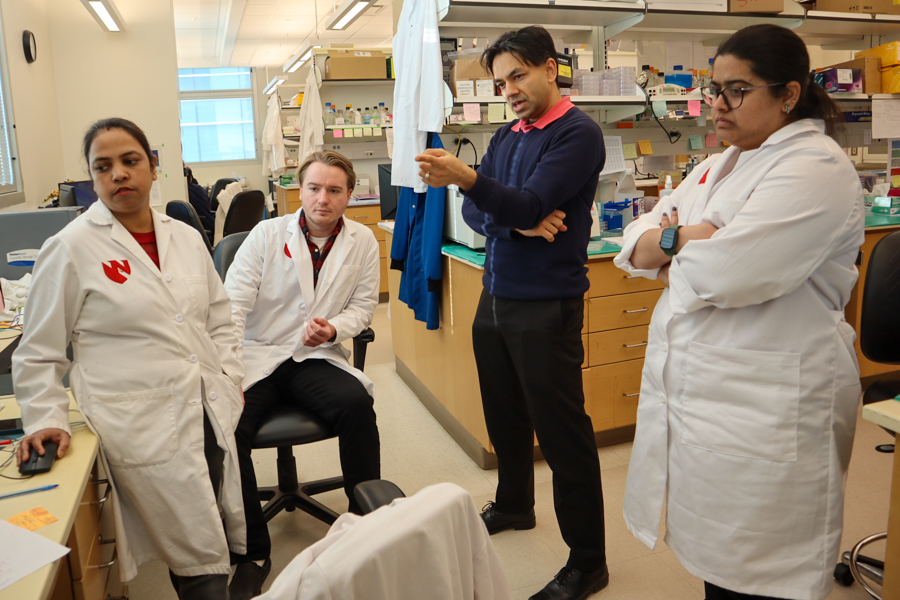 four people in lab looking at computer