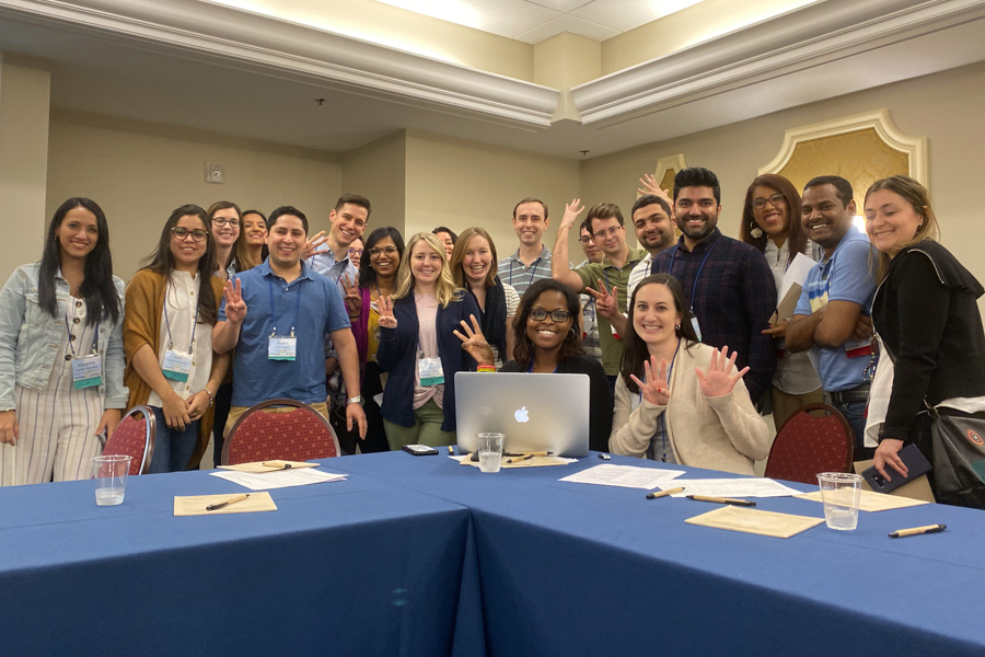 A group of ten gastroenterology fellows sitting behind a table at a conference